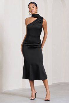 a woman is wearing a black dress with an asymmetrical neckline and high heels