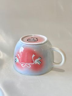 a white and red coffee cup sitting on top of a table