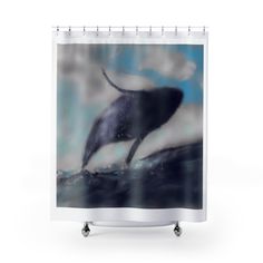 a shower curtain with an image of a whale jumping out of the water on a cloudy day