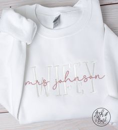 "This Wifey Sweatshirt is the perfect gift for any bride. This super soft sweatshirt is embroidered with the bride's last name on the front, making it a special, one-of-a-kind wedding gift. It's sure to make her feel like a Wifey! SWEATSHIRT DETAILS: - Bella & Canvas Unisex drop shoulder sweatshirt. - Combed & ringspun cotton/polyester. - Lightweight sweatshirt that is perfect to wear year round. - Thread colors:  White for WIFEY wording, Rose Gold for overlapping wording (Example: Mrs. \"last name\"). HOW TO ORDER: - Select your size from the drop down menu - For personalized items add your personalization to the \"Add your personalization\" field. - Add to cart - Select your shipping from the drop down menu. - Enter any additional information in the \"notes to seller\" field ★ If you are Long Sleeve Cotton Sweatshirt For Anniversary, Embroidered White Sweatshirt For Gift, White Sweatshirt With Letter Embroidery As Gift, Wifey Shirt, Bride Wedding Gift, Wifey Sweatshirt, Drop Shoulder Sweatshirt, Sweatshirt Details, Dropped Shoulder Sweatshirt