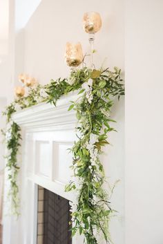 a mantel decorated with greenery and candles