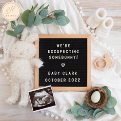 a baby announcement is displayed on a blanket next to a teddy bear and other items