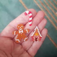 someone is holding some tiny pixel art pieces in their hand, including a gingerbread man and a candy cane