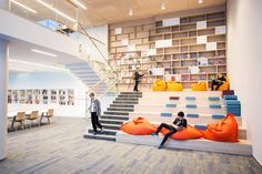 two people sitting on bean bags in the middle of a room with stairs and bookshelves