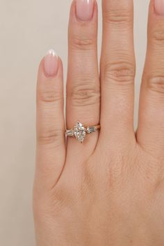 a woman's hand with a diamond ring on top of her left hand,