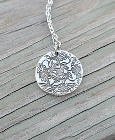 "This is an adorable circle pendant that has daisies and leaves stamped on it. It is silver plated and measures just over 3/4\". *Choose your necklace length that check out. The chain is stainless steel.  This will be sent to you in a gift box. This is perfect for anyone! Birthdays, anniversaries, jewelry for bridesmaids, gifts for Mom, or any other occasion. Please contact me if you have any custom requests or questions. Shipping is typically 4 to 6 days in the US, Or you can upgrade to Priority (2 to 3 days) or Express (1 to 2 days). International shipping is between 1 to 3 weeks, depending on your location. You can select an upgrade at checkout." Silver Etched Necklace With Flower Pendant, Silver Charm Necklace With Flower Charm, Silver Charm Necklace With Round Flower Charm, Silver Charm Necklace With Birth Flower Round Pendant, Silver Birth Flower Round Pendant Charm Necklace, Silver Flower Charm Necklace With Round Pendant, Dainty Silver Flower Necklace With Round Pendant, Silver Necklaces With Flower Charm And Round Pendant, Silver Dainty Flower Necklace With Round Pendant