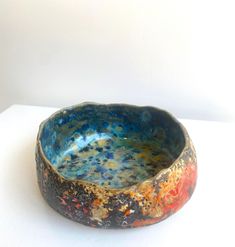 a bowl that is sitting on top of a white table with paint splattered it