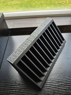 a close up of a metal object on a table near a window with grass in the background