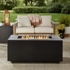 an outdoor fire pit sitting on top of a patio next to a couch and table