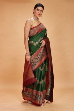 Look your ethnic best on special occasions in this green tussar Banarasi saree with maroon zari border. It has an antique zari red pallu and zari creeper. The saree comes with a matching blouse piece. Disclaimer: The shown stitched blouse on the model is for display purpose only. The saree comes with a matching blouse piece and finished with fall and piko. Banarasi Sari, Tussar Silk Sarees, Indian Clothing Store, Fashion Journals, Tussar Silk Saree, Banarasi Saree, Indian Clothing, Traditional Fabric, Banarasi Sarees