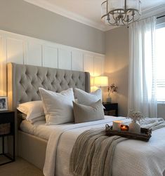 a bed with white linens and pillows in a bedroom next to a chandelier