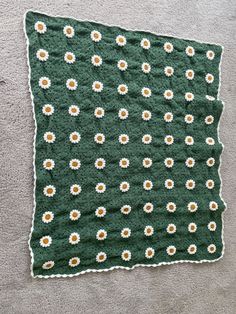 a green blanket with white and yellow flowers on it