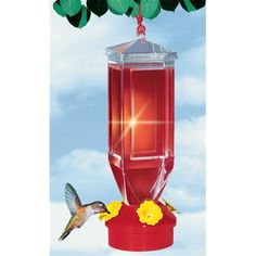 a hummingbird flying towards a red bird feeder with yellow flowers on it's side