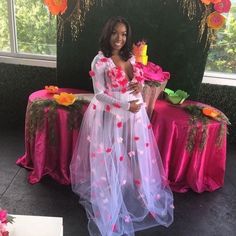 a woman standing in front of a table with pink and red decorations on it,