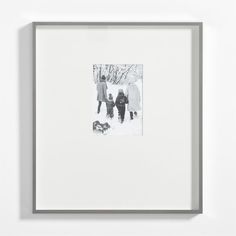 a black and white photo of two people walking in the snow with a dog behind them