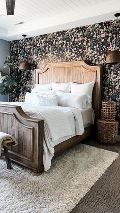 a bedroom with floral wallpaper and white bedding