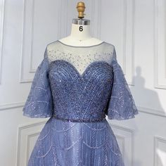 a blue dress on display in front of a white door with a wooden mannequin