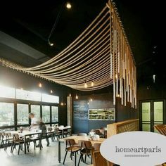 a restaurant with wooden tables and chairs in the middle, hanging from the ceiling above