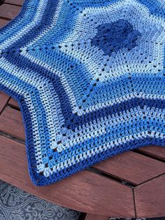 a blue crocheted blanket sitting on top of a wooden bench