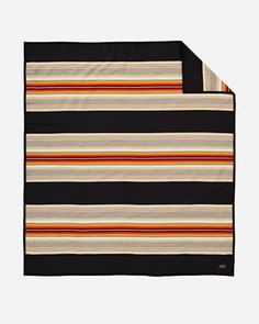 the black and white striped blanket is folded on top of an orange, yellow, and red