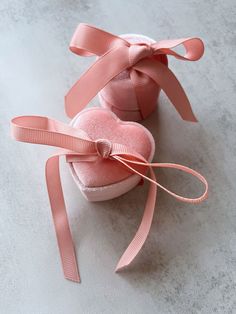 two pink heart shaped boxes with ribbons tied around them