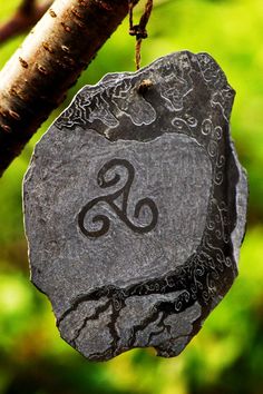 a stone hanging from a tree branch with the letter e on it's side