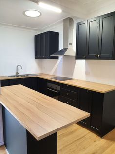 an empty kitchen with wooden counter tops and black cabinets