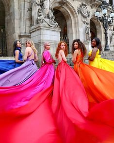 four beautiful women in long dresses are standing together on the steps outside an old building