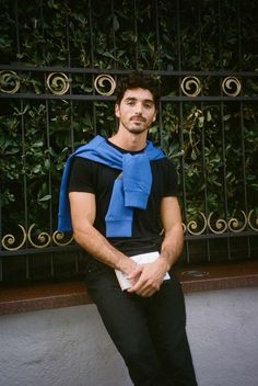 a man sitting on a bench with a blue scarf around his neck and black pants