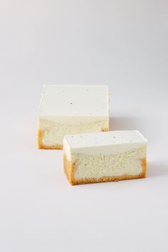 two pieces of cheesecake sitting next to each other on a white surface with one slice missing