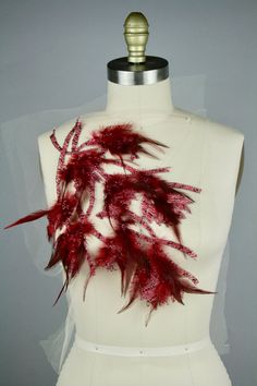 a white mannequin with red feathers on it