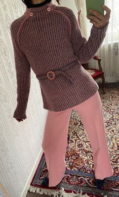 a woman taking a selfie in front of a mirror wearing pink pants and a sweater