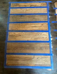 wood flooring being laid out on top of a wooden floor with blue tape around the edges