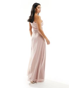 a woman in a long pink dress is looking back at the camera and she has her hand on her hip