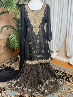 Ready to wear can ship same business day. Color     Black and gold  Fabric    shirt, dupatta (chiffon)                 Inner banarsi jamavar and also a soft                  Layer underneath                  Sharara fabric Banarsi chiffon  Embroidery details  Total handmade adda work Kora, Dabka, Stones, Pearls The fabric used in this dress is very high quality. Embroidery is very elegant and neat and gives designer dress. Very high quality nicely stitched stylish sharara suit. Size Large  Shoulder 17 Chest 22 Waist 21 Hips 23 Shirt length 35 Sharara length 44 This dress is available in size  large  ready to wear and  can ship immediately. if you need same dress in other sizes  can be made to your size contact me 818-687-2408  for your customize size. Thanks Semi-stitched Gold Chanderi Lawn Suit, Elegant Semi-stitched Sharara With Dabka Work, Gold Floor-length Sets For Eid, Gold Floor-length Sharara For Transitional Season, Gold Chinon Sharara For Eid, Gold Unstitched Sharara With Resham Embroidery, Unstitched Gold Sharara With Resham Embroidery, Formal Semi-stitched Jamawar Dupatta, Semi-stitched Gold Sharara For Designer Wear