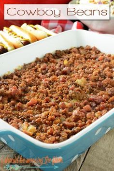 a casserole dish filled with meat and beans next to hotdog buns