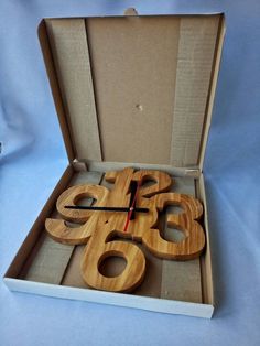 a wooden clock in a cardboard box on a blue tableclothed surface with the numbers sixty six and eight