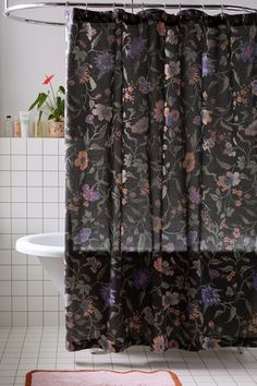 a bathroom with a floral shower curtain and rug