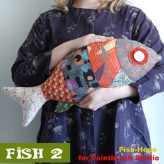 a girl holding a fish pillow in her hands