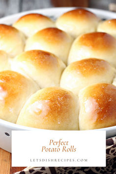 a white dish filled with bread rolls on top of a wooden table