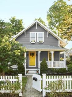 a gray house with yellow door and white picket fence