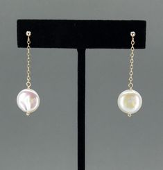 Add a touch of elegance to any outfit with our Coin Pearl Dangle Earrings. Available in 14k gold filled or sterling silver, these earrings are nickel-free and hypoallergenic, making them ideal for sensitive ears. Featuring a stunning 12mm (0.5 inch) coin pearl with gorgeous luster, these earrings dangle gracefully from a delicate chain attached to a ball post. With a total drop length of 1.5 inches, they are perfect for any dressy occasion, including weddings, bridal jewelry, and for bridesmaids. Each pair of earrings arrives beautifully packaged in a gift box. Material Options: 14k gold filled or sterling silver Hypoallergenic: Nickel-free, perfect for sensitive ears Elegant Design: 12mm (0.5 inch) coin pearl with beautiful luster Graceful Drop: 1.5 inches total length, with the pearl dan White Gold Clip-on Drop Earrings, Clip-on Dangle Earrings In Yellow Gold, Yellow Gold Dangle Plug Earrings For Formal Events, Yellow Gold Clip-on Dangle Jewelry, Yellow Gold Clip-on Dangle Earrings, 14k Gold Round Pearl Earrings, White Long Drop Earrings Fine Jewelry, Anniversary Yellow Gold Pearl Drop Earrings, Classic Round Linear Earrings