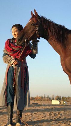 a woman standing next to a brown horse