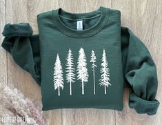 The coziest pine tree sweatshirt, perfect for camping and hiking trips in the forest! MATERIAL ✨ Sweatshirt sizes are Unisex, please refer to sizing chart in listing photos ✨ 50% cotton, 50% polyester ✨ Medium fabric weight PRINTING ✨ DTG Printed  CARE ✨ Machine wash: warm (max 40C or 105F) ✨ Do not iron ABOUT My love for design and clothing is what inspired the creation of this store.  During lockdown, I had so much free time and I have always had a dream to start my own business, and from this Green Long Sleeve Sweatshirt For Outdoor Activities, Green Winter Sweatshirt For Outdoor Activities, Green Crew Neck Top For Camping, Green Fall Sweatshirt For Outdoor Activities, Green Sweatshirt For Fall Outdoor Activities, Green Sweatshirt For Outdoor Fall Activities, Winter Hiking Crew Neck Top, Green Crew Neck Sweatshirt For Outdoor, Green Tops For Outdoor Activities In Fall