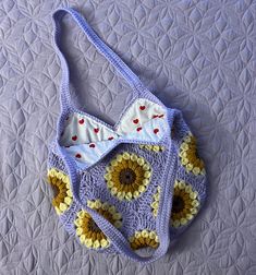 a crocheted purse sitting on top of a bed next to a white blanket