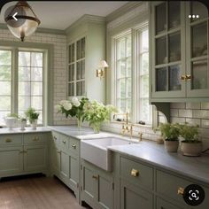 a kitchen filled with lots of green cabinets and white counter tops next to a window