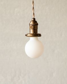 a white light hanging from a ceiling with a brown cord attached to the end of it