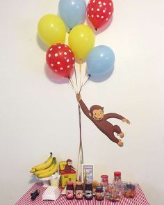 a table topped with lots of balloons next to a wall mounted monkey on the wall