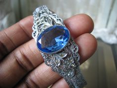 A beautiful Art Deco blue and clear paste floral filigree bangle bracelet. It measures 3/4'' at widest Measures 2 3/8'' x 2'' across the inside, and is 6 3/4'' along the inside. in very good condition with some graying and yellowing to the clear paste stones Wedding Filigree Bangle, Wedding Filigree Bangle Jewelry, Blue Victorian Filigree Jewelry, Victorian Bangle Bracelets For Wedding, Victorian Bangle Bracelet For Wedding, Silver Filigree Bracelets For Wedding, Wedding Filigree Adjustable Bracelets, Wedding Filigree Bangle Bracelets, Adjustable Filigree Bracelets For Wedding