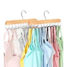 several shirts hanging on a wooden hanger in front of a white wall with multiple colors